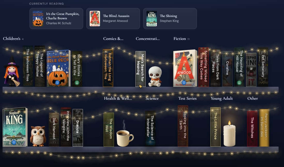 A Showcase of Halloween reads on a midnight-blue wall, with fairy lights strung along the shelves and a witch, a skeleton, an owl, a coffee and a lit candle between the books